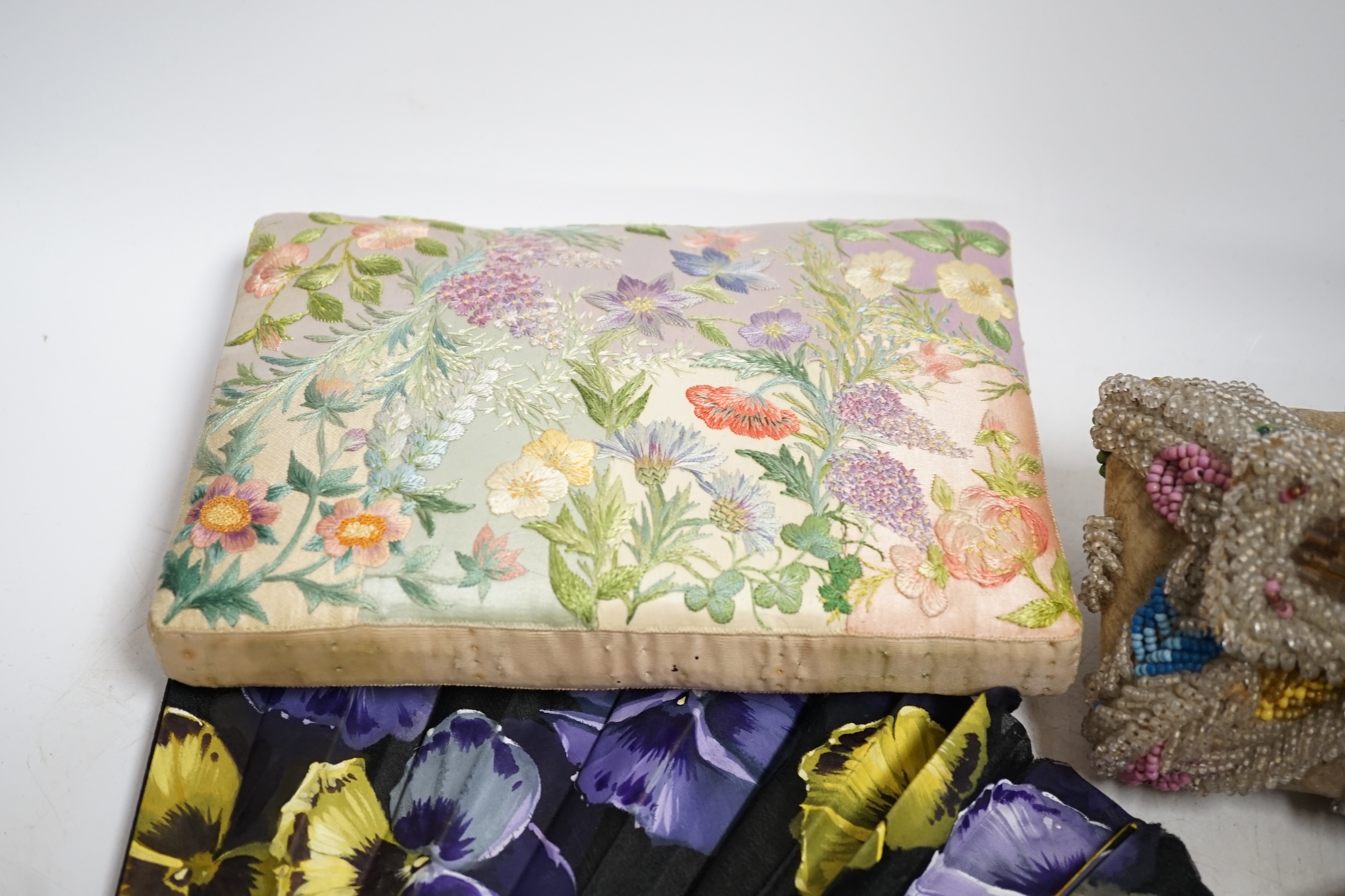 A Chinese 1920’s boxed carved bone and silk embroidered dragon fan, a larger European pansy decorated fan, a bead worked basket, a mat, two cut steel necklaces, an embroidered pin cushion, an evening bag and a misers pur